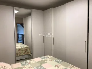 Quarto com cama e espelho refletindo outro ambiente.