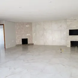 Imagem de um ambiente interno amplo com paredes claras e piso de mármore.