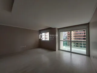 Ambiente interno de uma sala ampla com piso de madeira clara.