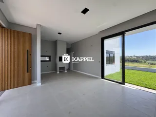 Ambiente interno amplo com piso claro e porta de vidro que dá acesso a um jardim.