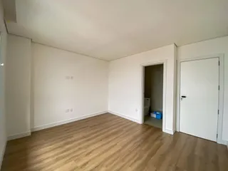 Foto de um cômodo interno com piso de madeira clara e paredes brancas.