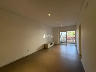 Sala de estar ampla com piso de cerâmica e paredes brancas.