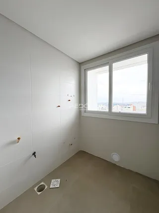 Vista de um canto interno de um imóvel com paredes brancas e piso claro.
