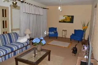 Sala de estar com sofá e cortinas claras.