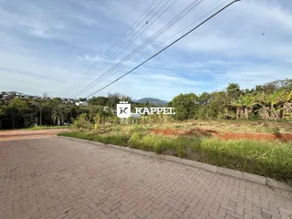 Vista externa de uma estrada pavimentada com vegetação e colinas ao fundo.