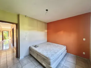 Quarto com cama grande e paredes em tons de laranja e creme.