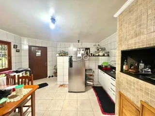 Interior de uma cozinha e sala de estar com piso de cerâmica clara.