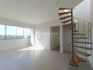 Sala de estar ampla com grande janela e escadaria moderna.