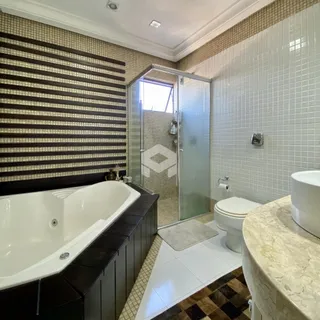 Foto de um banheiro com banheira e box de vidro.