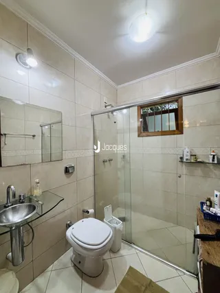 Foto interna de um banheiro com revestimento de cerâmica e box de vidro.