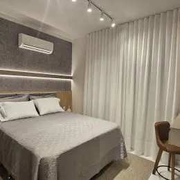 Quarto com cama e ar-condicionado em ambiente interno.