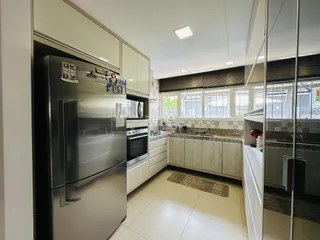 Cozinha moderna com armários brancos e eletrodomésticos de aço inoxidável.
