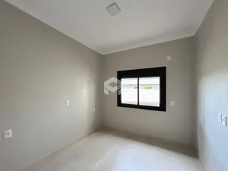 Vista interna de um cômodo com paredes cinzas e uma grande janela.
