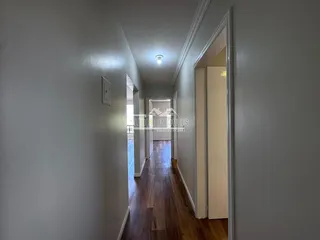 Corredor interno com piso de madeira e paredes claras.