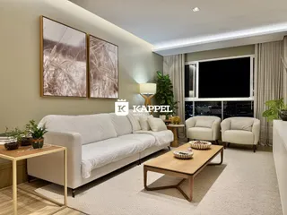 Sala de estar com sofá branco e vista da cidade noturna.