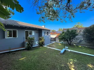 Vista externa de uma residência com jardim e gramado.