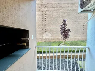Vista da fachada de um imóvel com parede de tijolos à vista e grade de segurança.
