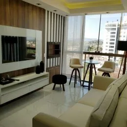 Sala de estar com sofá branco e televisão em um ambiente moderno.