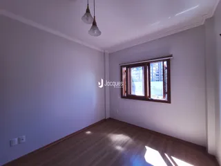 Uma sala com piso de madeira e janela de vista para a cidade.