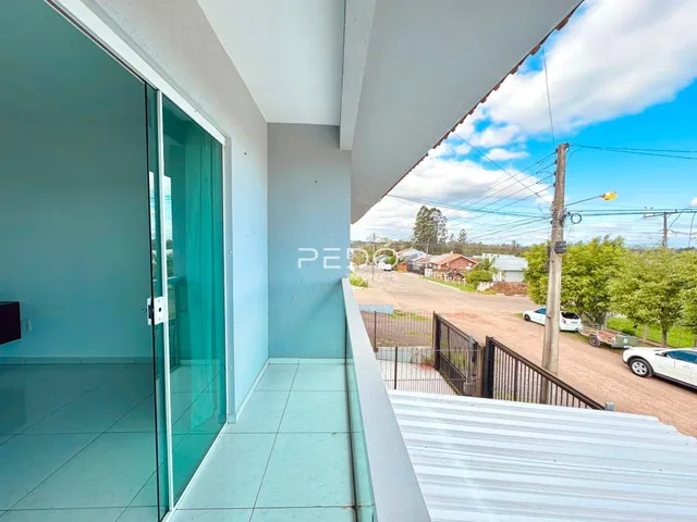 Vista interna de uma sala com porta de vidro abrindo para uma varanda.