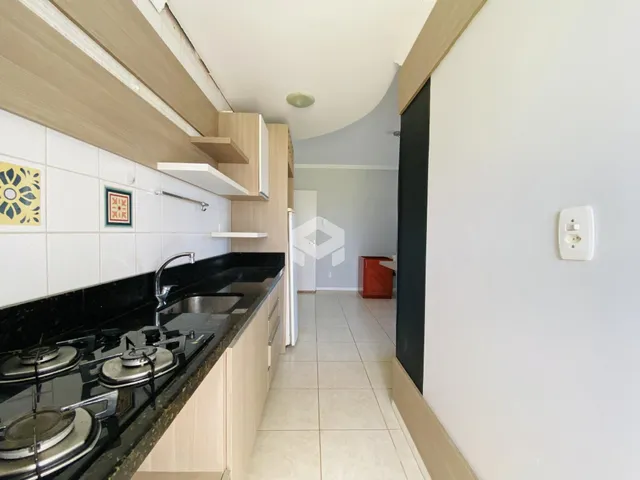 Cozinha moderna com bancada escura e armários claros.