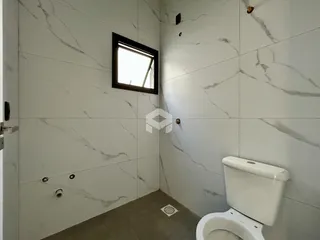 Foto de um banheiro com paredes em mármore branco e piso cinza.