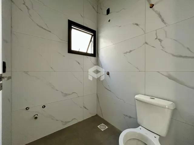 Foto de um banheiro com paredes em mármore branco e piso cinza.