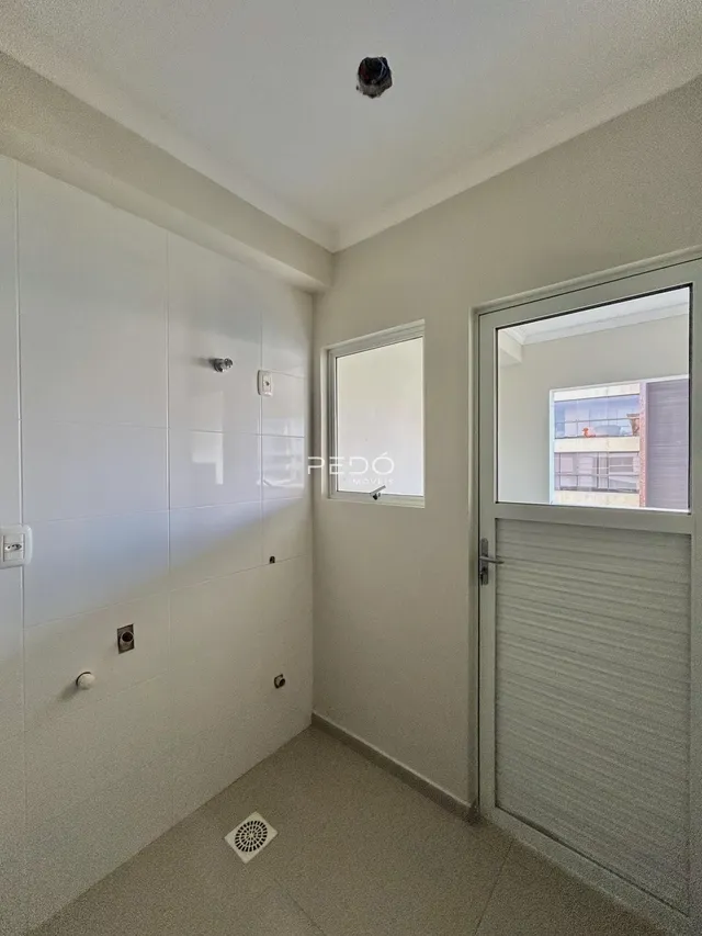 Hall de entrada com paredes brancas e armários embutidos.