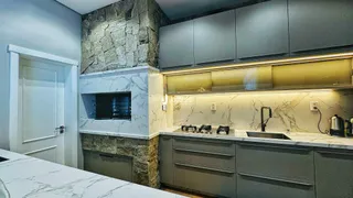Cozinha moderna com armários cinzas e revestimento de pedra.