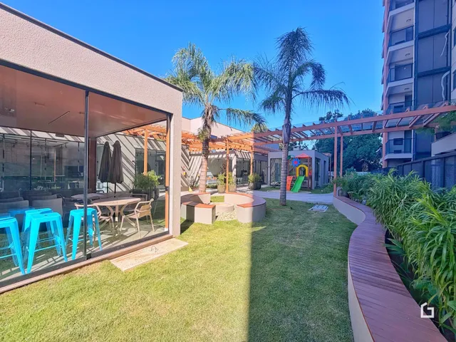 Vista externa de um jardim com palmeiras e deck de madeira.