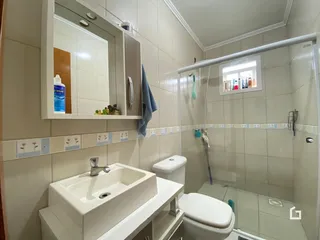 Foto interna de um banheiro com azulejos brancos e bancada branca.