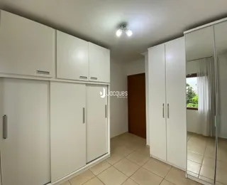 Quarto com armários embutidos brancos e espelho na parede.
