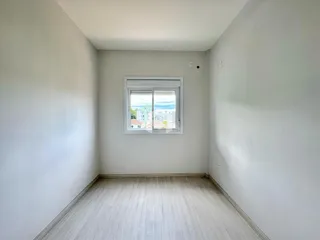 Ambiente interno de um cômodo com piso de madeira e janela.