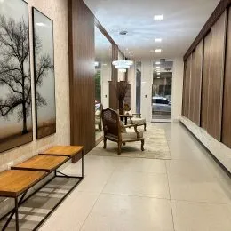 Corredor interno com revestimento de madeira e piso claro.