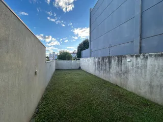 Vista externa de um quintal gramado entre duas paredes.
