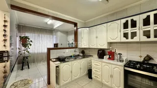 Cozinha com armários brancos e piso claro em imóvel no Brasil.