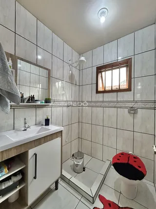 Foto de um banheiro com revestimento cerâmico e bancada branca.