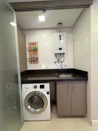 Foto de uma área de serviço com máquina de lavar e pia.