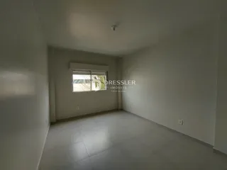 Imagem interna de um ambiente com paredes brancas e piso claro.