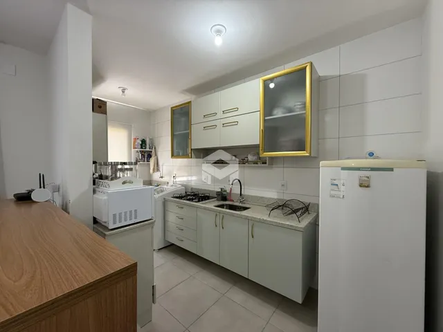 Interior de uma cozinha com armários brancos e piso claro.