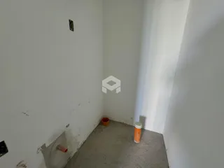 Vista interna de um corredor com paredes brancas e piso de concreto.