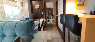 Sala de estar com sofá azul e piso claro na residência.