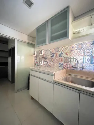 Mostra uma seção da cozinha com armários e revestimento de azulejos coloridos.