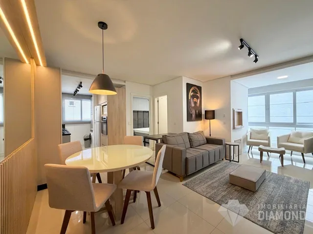 Sala de estar com mesa de jantar e sofá em um apartamento em Lajeado.
