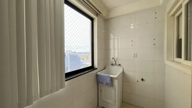 Banheiro com paredes brancas e janela.