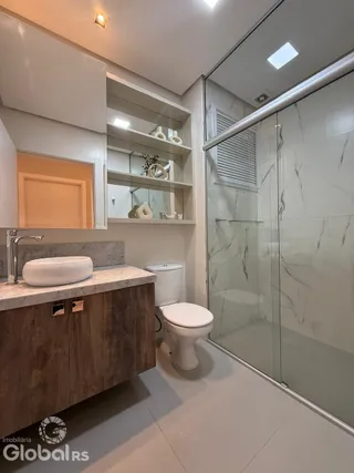 Banheiro moderno com box de vidro e bancada de madeira.