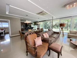 Sala de estar ampla com sofá de couro e portas de vidro que dão vista para o exterior.