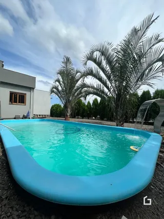 Foto de uma piscina externa com vegetação ao redor.