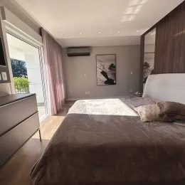 Um quarto com cama grande e paredes em tons neutros.