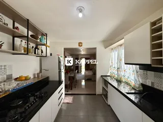 Cozinha moderna com armários brancos e bancadas escuras.